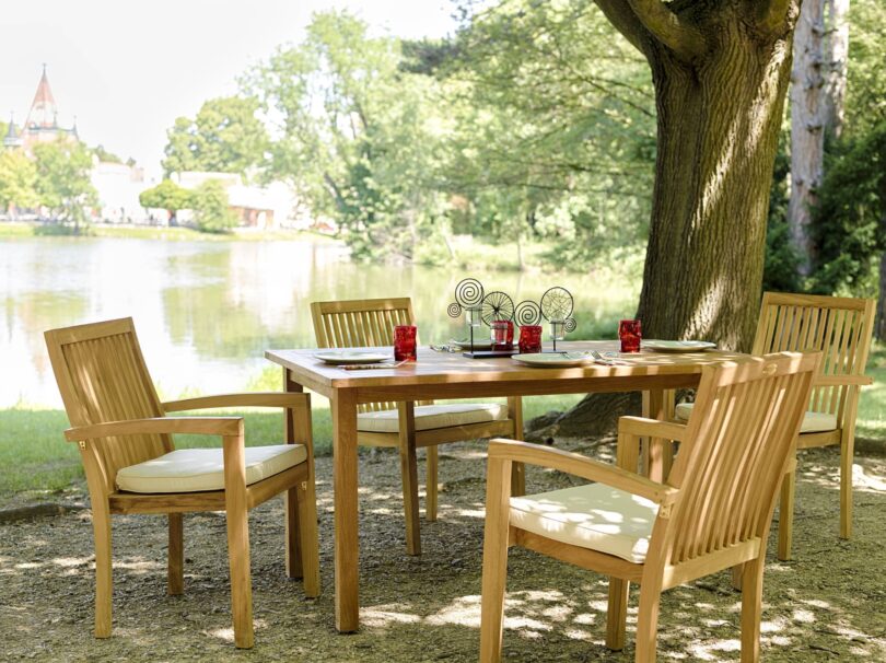 Drevený záhradný set Java od spoločnosti Teak-it sa skladá zo stola a štyroch stohovateľných stoličiek s mosadzným kovaním.